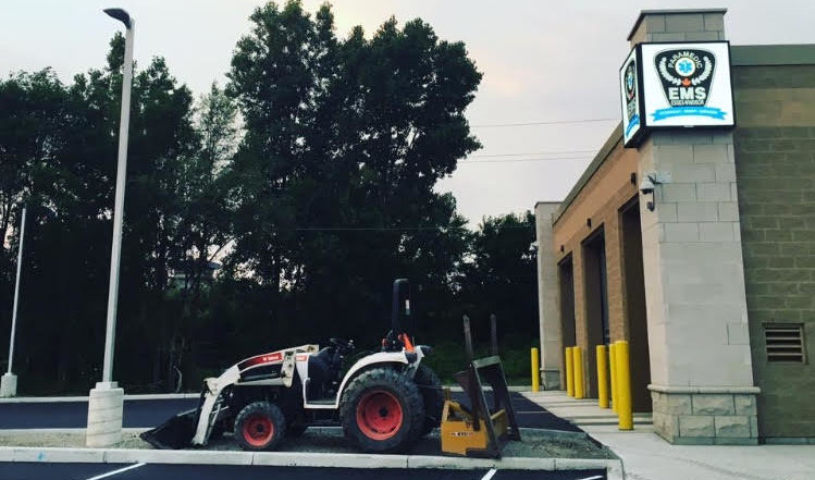 Construction vehicle in front of EMS building.