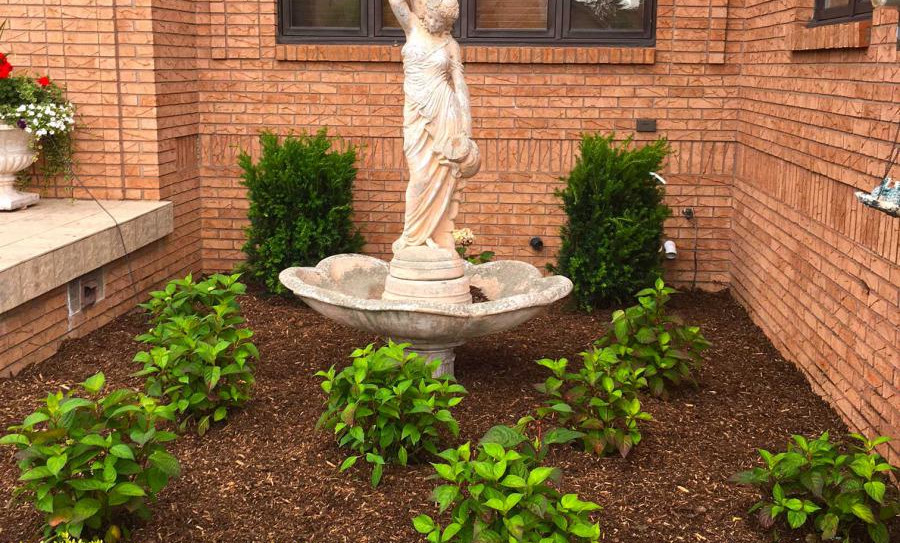 Shrub landscaping work done around outdoor statue.