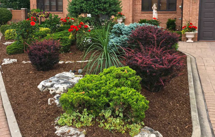 Residential landscaping work including mulch, stones, and shrubbery.